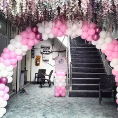 A beautiful entrance for a Naming Ceremony. A pink and white balloon arch is complemented by hanging floral arrangements, creating an elegant and welcoming entryway for guests.