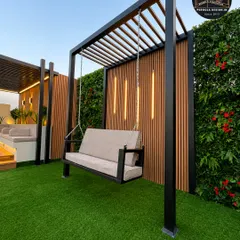 Another view of the elegant freestanding pergola swing. The robust black metal frame ensures stability, while the plush seating invites you to relax and enjoy your outdoor space.