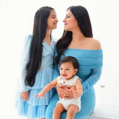 A mother's love captured in a single glance. This portrait of a beautiful mamma with her two children showcases the tender bond between them in a clean, bright studio setting.