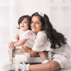 A big sister's loving hug. She holds her baby sister with such tenderness and pride in this beautiful, light-filled studio portrait.