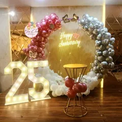 A stunning 25th anniversary celebration with a balloon ring in metallic red, silver, and white, complemented by a large marquee number '25'.