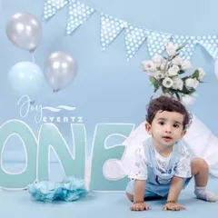 A classic blue-themed cake smash for a baby boy turning one. The set features a large "ONE" sign, blue and silver balloons, and polka dot bunting, providing a perfect backdrop for this milestone moment.