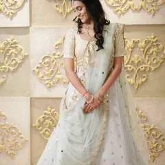 A dreamy pastel lehenga for a bride's reception. The light blue skirt is adorned with scattered gold motifs, paired with a sequined gold blouse for a touch of sparkle.