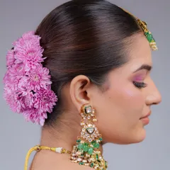 A side profile of a classic bridal bun, showing how the fresh flowers are woven into the hair. This angle highlights the beautiful silhouette of the updo against the bride's profile.