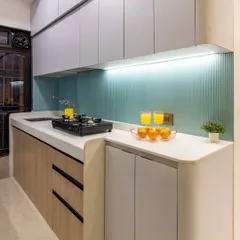 A glimpse of the "after" in this kitchen renovation, showcasing the clean lines, pastel blue backsplash, and a mix of wood and grey laminates.