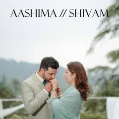 A classic, romantic engagement portrait of a man kissing his fiancée's hand against a soft mountain backdrop.