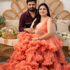 A warm and loving portrait of the couple seated together on our boho set. The rich peach color of the gown and the earthy tones of the decor create a cozy and inviting atmosphere for this pregnancy photoshoot.