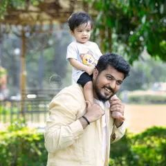 A father's joy is evident as he carries his smiling toddler on his shoulders during an outdoor family shoot. A classic shot full of happiness.