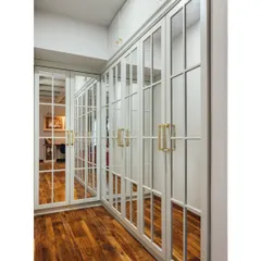 For this walk-in closet, we designed floor-to-ceiling mirrored wardrobes with a classic panel design. The mirrors make the narrow space feel expansive, and the custom brass handles add a touch of luxury.