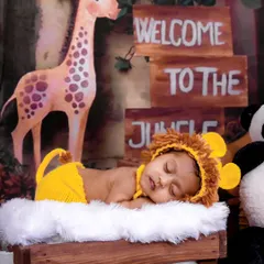 Welcome to the jungle! This little one is dressed as a tiny lion, sleeping peacefully in a setup complete with a giraffe, panda, and jungle signs.