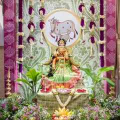 A divine setup for a Varalakshmi festival. We decorated the goddess with rich fabrics and fresh flowers, set against a backdrop featuring Kamadhenu motifs and surrounded by lush greenery to create a truly sacred space.