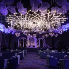 The same grand hall viewed from the entrance, showing the powerful first impression created by the custom lighting and stage design. The symmetrical arrangement of seating leads the eye towards the main stage, building anticipation for the event.