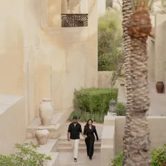 Capturing a candid moment as the couple walks through the beautiful, sand-colored architecture of a Dubai resort. This image tells a story of a shared journey in an exotic location.