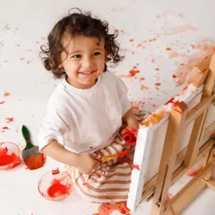 The proud smile of a young artist with her masterpiece. These sessions are all about capturing pure, messy, colorful joy.