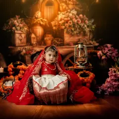 A full-length portrait showing the elegance of the traditional attire. The warm, glowing backdrop with flowers and lanterns adds a magical, festive feel.