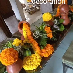 A rustic and charming table arrangement featuring marigold garlands, floral spheres, and small earthen pots. This design combines traditional flowers with natural elements for a warm and inviting look.