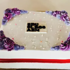 A blueberry sheet cake with purple floral corners, perfect for a large gathering.