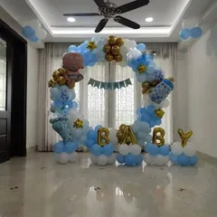 A lovely "BABY" themed decoration for a baby shower or welcome party. This setup features a full balloon ring in blue, white, and gold, with "BABY" foil letters in the center.