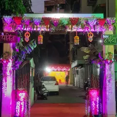 A stunning entrance gate for a Haldi ceremony at night. The combination of traditional decor, floral arrangements, and modern purple lighting looks fantastic.