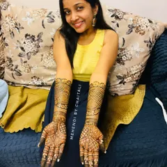 A happy client showing her engagement mehendi. The design is intricate and extends up the forearms, perfect for this special celebration in Mumbai.