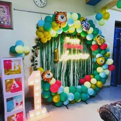 A fun jungle-themed first birthday party. I created a balloon ring with animal foil balloons and a green fringe backdrop, along with a light-up "1" and "BABY" boxes for the perfect photo corner.