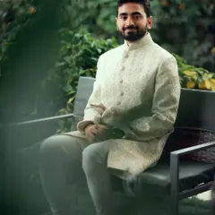 A relaxed portrait of the groom in his elegant sherwani, waiting in a garden before the ceremony.