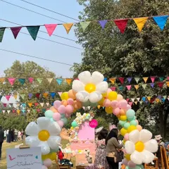 A welcoming entrance with a large, daisy-themed balloon arch and colorful bunting flags, setting a festive tone for the birthday party.