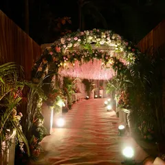 We create enchanting pathways for your guests. This entrance features a lush floral arch and a ceiling of hanging pink blossoms, warmly lit to welcome everyone into the celebration.
