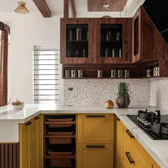 In 'Project Varnika', the U-shaped kitchen is brought to life with vibrant mustard yellow cabinets and a terrazzo dado. I included open wicker basket drawers for easy access to vegetables.
