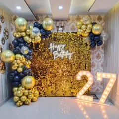 A dazzling gold sequin wall makes a statement at this 27th birthday party. Framed with gold and silver balloons and paired with marquee numbers, it creates a truly glamorous focal point.