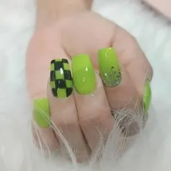 A bold and graphic look with bright lime green nails, a checkerboard accent nail, and a touch of glitter.