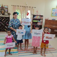 The children proudly present their ant queen drawings. This craft activity followed a story about good manners and keeping promises, with each child coloring their own royal ant.
