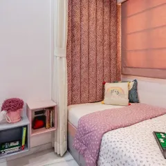 This cozy bedroom corner is designed with a soft pink and grey palette. The plush, channel-tufted headboard adds a touch of luxury and comfort, while the floating bedside shelf provides a convenient spot for books and essentials.