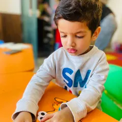 A student concentrates on assembling his paper craft. These quiet, focused moments are just as important as the high-energy drama games for a well-rounded experience.