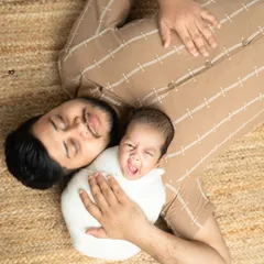 A sleepy yawn from the baby and a peaceful smile from dad. This candid, top-down shot captures a real and relatable moment of life with a newborn.