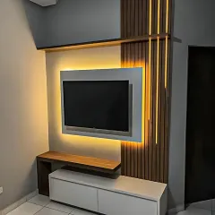 A modern TV unit design where ambient backlighting makes the screen appear to float. The vertical wood slats add texture and contrast to the minimalist white console.