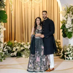 A classic portrait of a stunning couple, Nikki & Avin, at their reception. They stand against a backdrop of white flowers, exuding elegance and happiness.