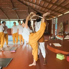 In our advanced training, we explore complex asanas with care. I use a strap to help a student work towards Svarga Dvijasana (Bird of Paradise Pose), demonstrating how props can make challenging postures more accessible.