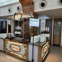 This dedicated station for plates is part of a larger, ornate buffet setup. The design ensures smooth guest flow and adds to the overall aesthetic of the event.