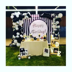A chic black, white, and silver birthday setup for an outdoor evening party. We created a stylish photo backdrop with a striped panel, a custom 'Happy Birthday' sign, and two beautiful balloon columns.