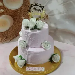 A classic two-tiered cake with a textured buttercream finish and white sugar roses. A simple, elegant design that's perfect for any celebration.