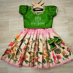 A lovely Kalamkari lehenga with a bird and flower motif. The green blouse has delicate embroidery, and the set is finished with cute bow-shaped tassels.