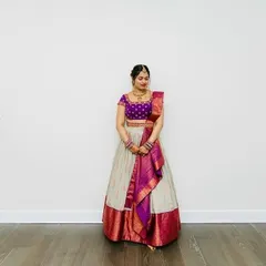 The bride stands gracefully in her ivory and purple lehenga, a picture of timeless elegance.