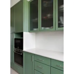 The kitchen in our Collectors House features custom cabinetry in a soothing sage green. Fluted glass on the upper cabinets adds a layer of texture and visual interest, partially obscuring the contents for a clean look.