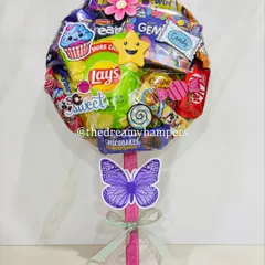 A close up of one of my giant lollipop hampers, bursting with a fun assortment of snacks like Lays, Kinder Joy, and various candies. These are always a huge hit at birthday parties and can be customized to include your child's favorite treats.