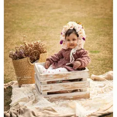 A dreamy outdoor first birthday shoot in a beautiful Gurugram park. This little one, snug in a rustic crate with a floral bonnet, looks like she's straight out of a storybook.