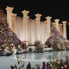 The balance between grandeur and simplicity. We created these magnificent 22-foot Roman pillars as a sleek, monotone backdrop, allowing the overflowing jewel-toned florals to provide a burst of life and color.