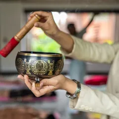 A wellness practitioner uses a traditional Tibetan singing bowl during a sound bath. The vibrations are designed to reduce stress, balance your energy, and promote a state of deep relaxation.
