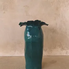 A tall, elegant vase with a ruffled rim and a rich, glossy green glaze. This piece is designed to be a statement, bringing a touch of nature's drama indoors.