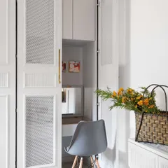 Functionality is hidden in plain sight. This elegant wardrobe features pocket doors that open and slide back to reveal a compact, fully functional study nook, complete with a desk and shelving. It is a perfect solution for maximizing space in a bedroom.